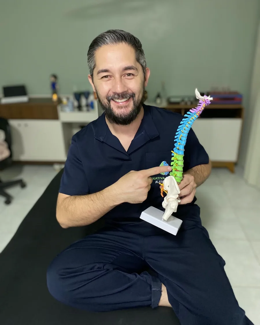 Alessandro Tiago Komido segurando um modelo anatômico da coluna